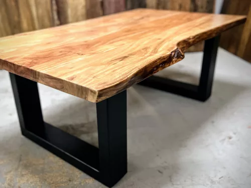 Une table de salon en bois massif avec des pieds en acier en forme de U