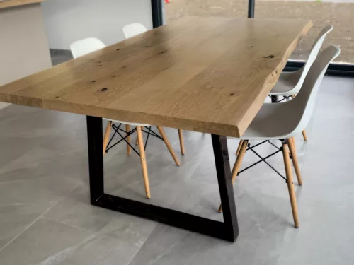 Une table avec un pied table en acier noir en forme de trapèze