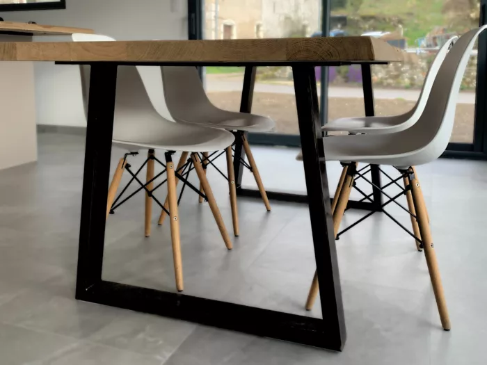 Une table avec des pieds en acier en forme de trapèze
