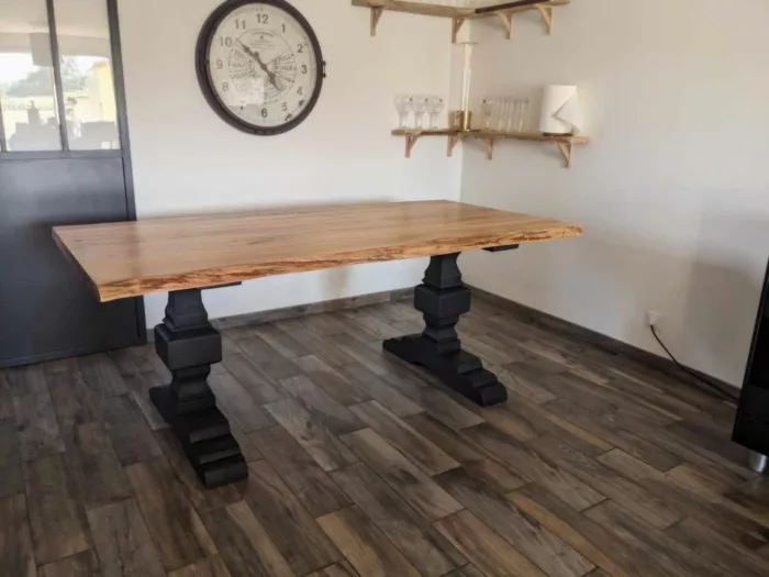 Un salon avec une table à manger avec deux pieds de table style monastère en bois