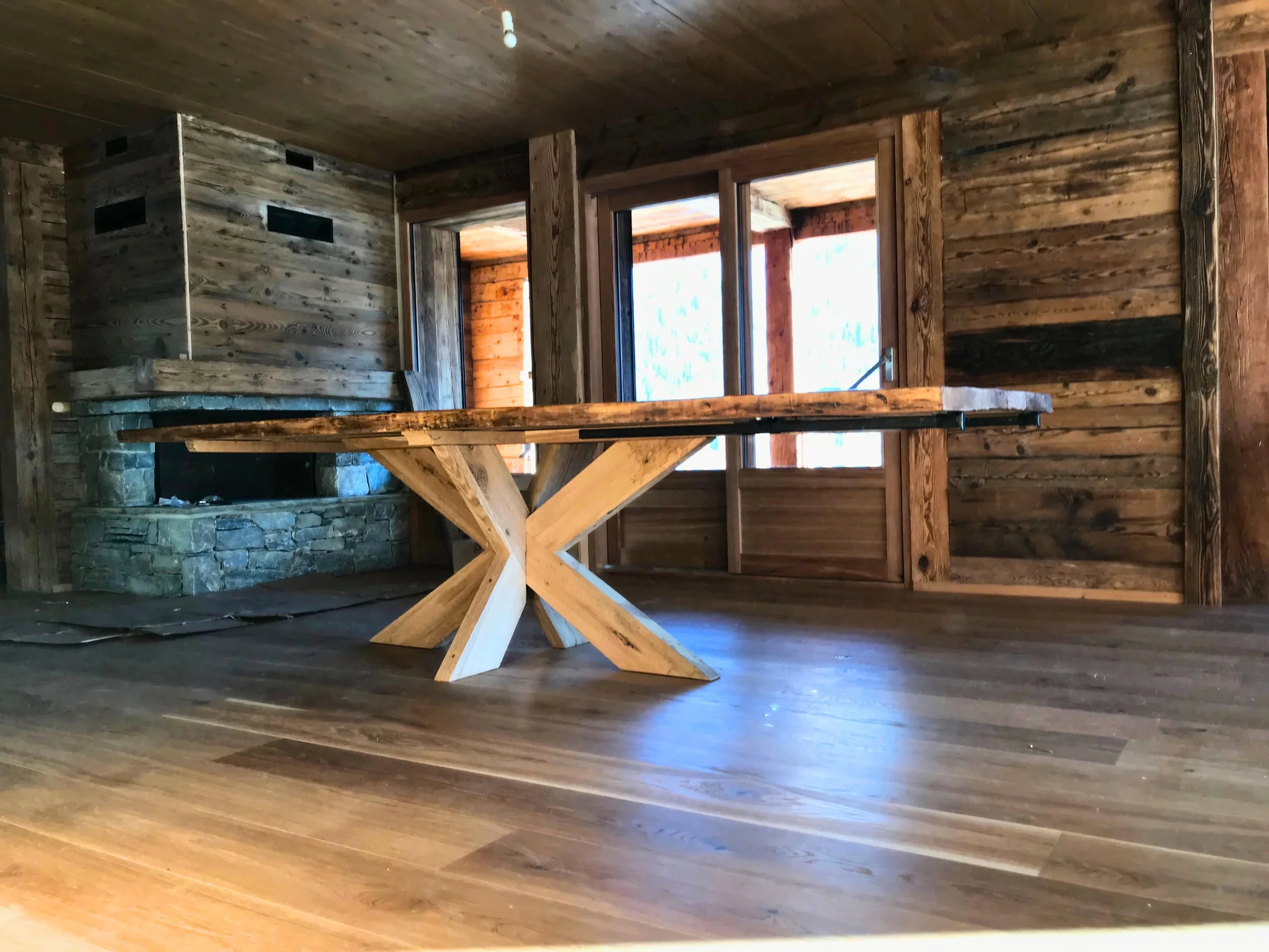 Une table avec un pied central en bois dans un chalet en bois